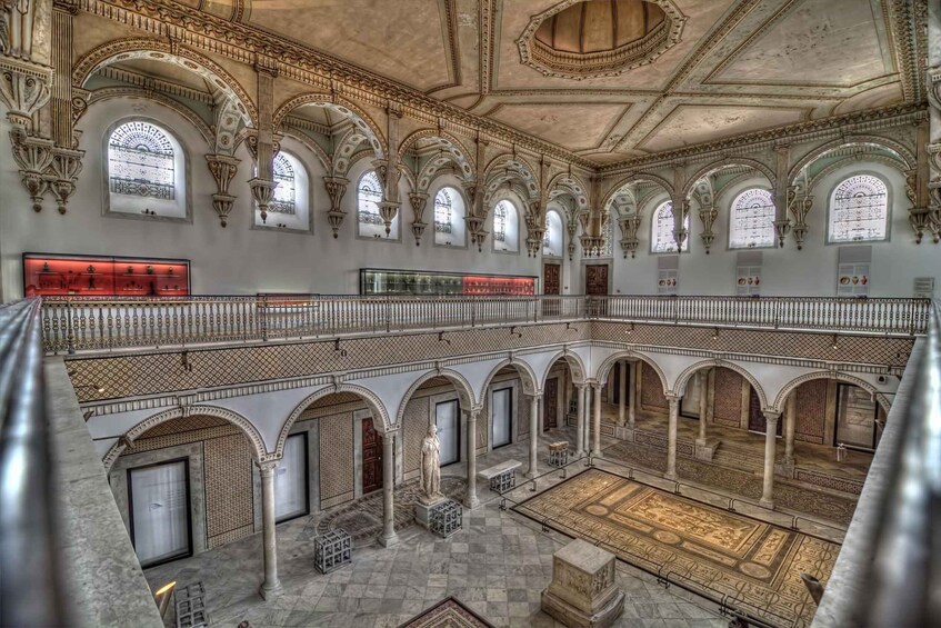 A grand interior with ornate arches, a central courtyard, and a glass display case. 5