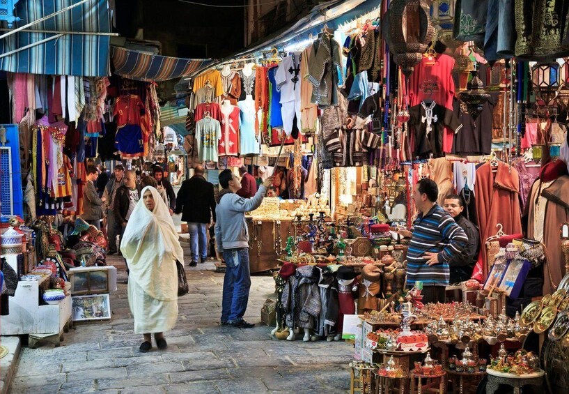 A bustling market with various stalls selling textiles, jewelry, and other goods. 4
