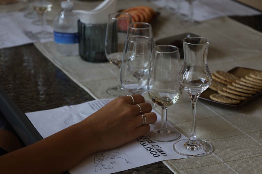 A table with wine glasses, a water jug, and a plate of crackers. 1
