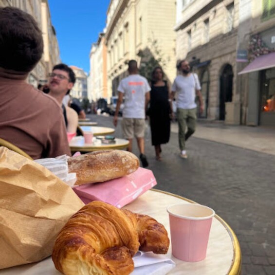 A street scene with people walking, a building, and a table with food items. 4