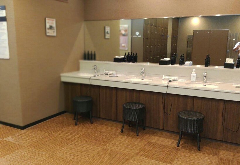 A modern bathroom with a long vanity, three sinks, and three wicker stools. 4