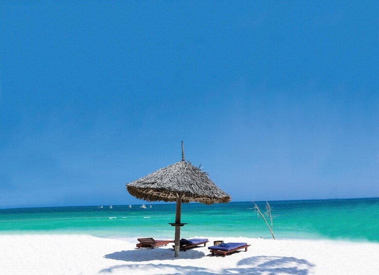A beach with a thatched umbrella, white sand, and turquoise water. 3