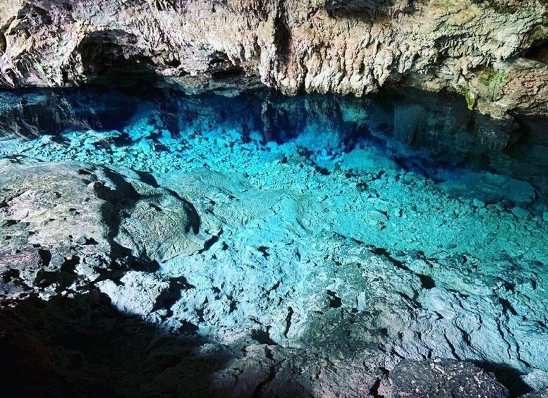 A cave with turquoise water and rocky formations. 2