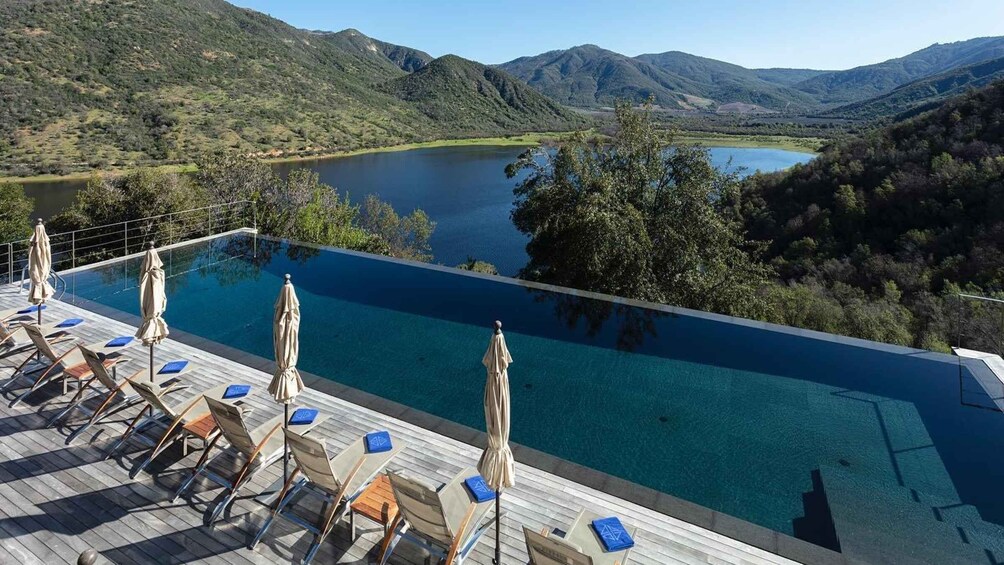 A swimming pool with lounge chairs and umbrellas overlooking a lake and mountains. 3