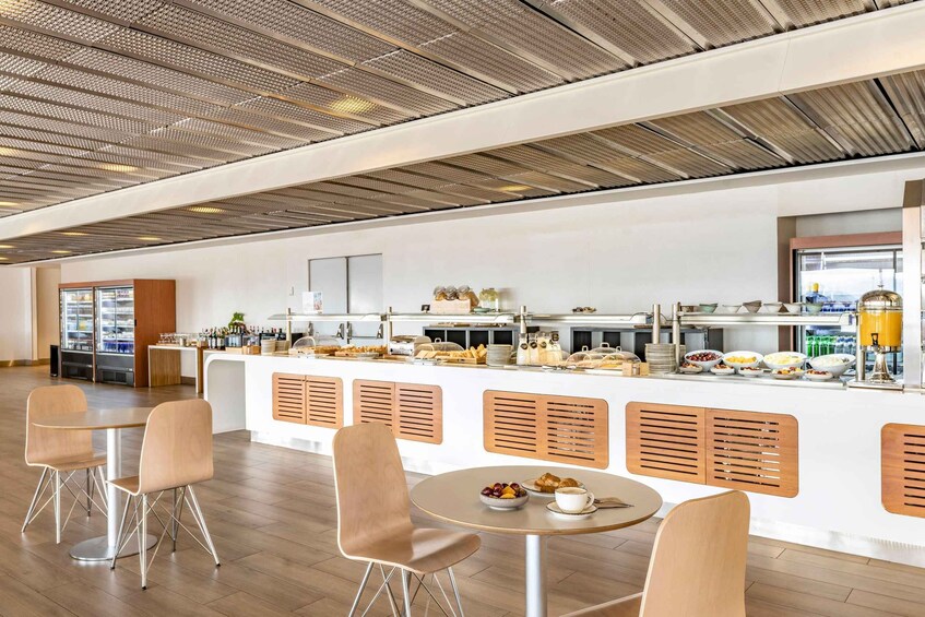 A modern cafe interior with a wooden ceiling, white walls, and a counter with various food items. 1
