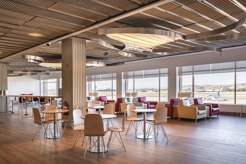 A spacious airport lounge with modern seating, large windows, and a ceiling with a unique pattern. 5