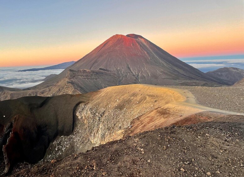 Un paysage volcanique caractérisé par un sommet montagneux imposant, une route sinueuse et une vallée enveloppée de nuages. 3