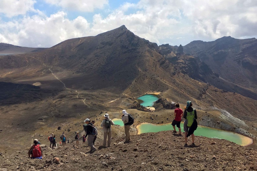 Un groupe de randonneurs sur un sentier de montagne, avec un lac et un ciel dégagé. 1