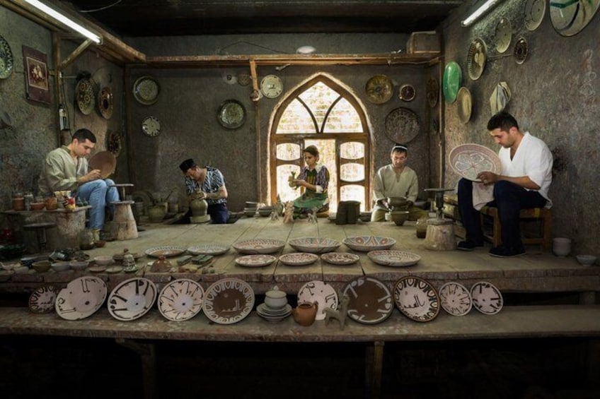A pottery workshop with artisans working on ceramic pieces. 1