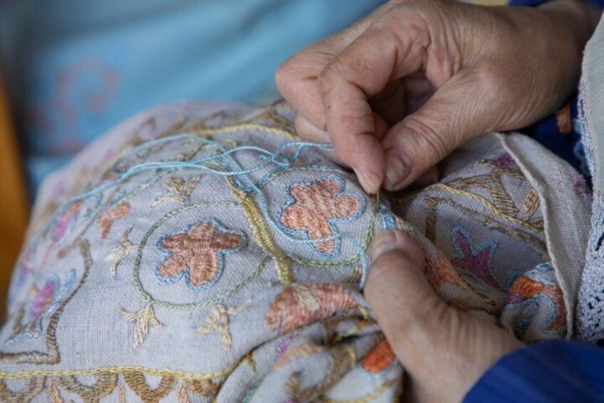 Hands embroidering a fabric with floral patterns. 5