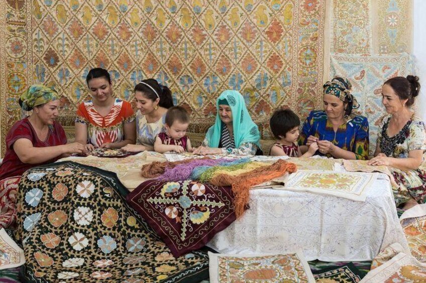 A group of people engaged in a craft activity, surrounded by patterned textiles and fabrics. 4