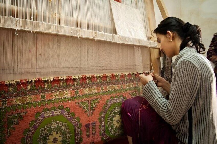 A person weaving a colorful textile on a loom. 2