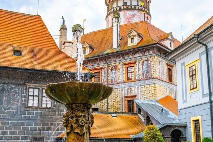 A historic building with a colorful facade, a fountain, and a tower with a clock. 1