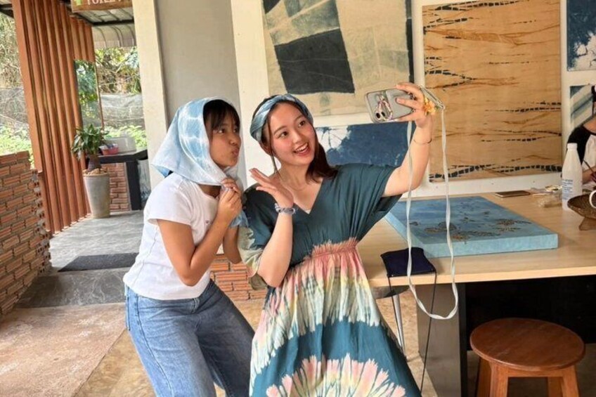 Two people taking a selfie, a table with art supplies, and a brick wall. 2