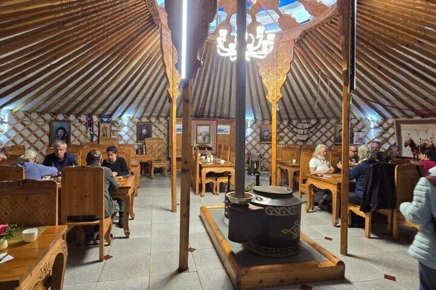 A traditional yurt with wooden furniture and a central fire pit. 2