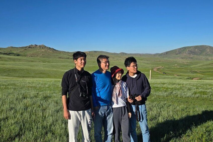 A group of people standing in a grassy field with rolling hills in the background. 3