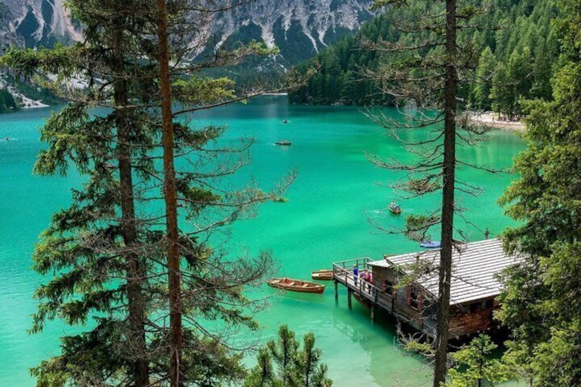 A turquoise lake surrounded by pine trees, a wooden dock, and a cabin. 1