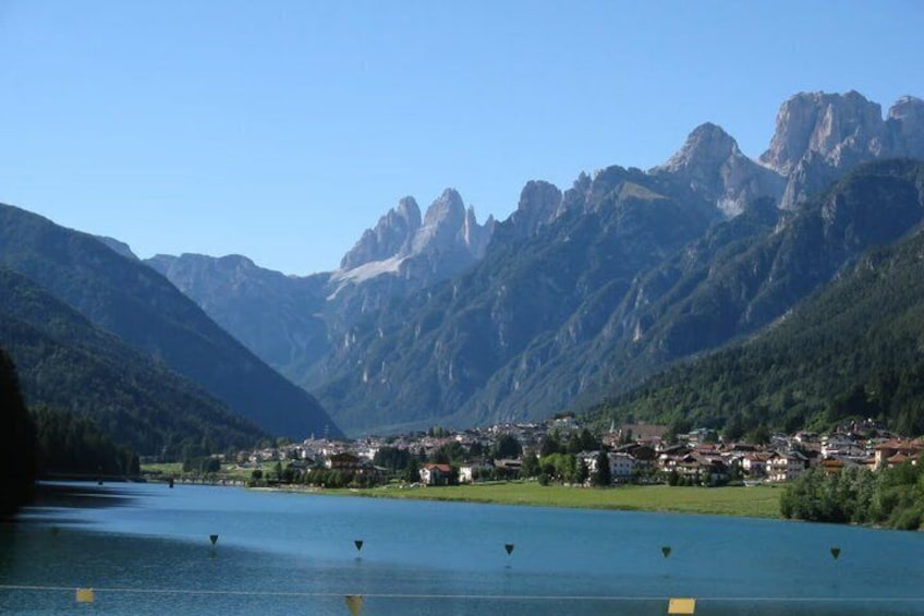 A lake with mountains in the background, a town in the middle, and a clear sky. 2