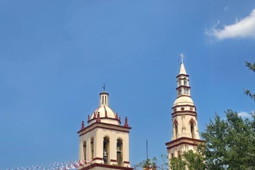 A church with a bell tower and a dome against a clear blue sky. 1