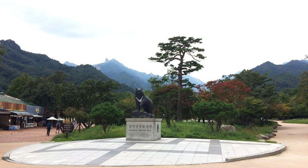 Eine Statue eines Bären in einem Park, im Hintergrund Berge. 4