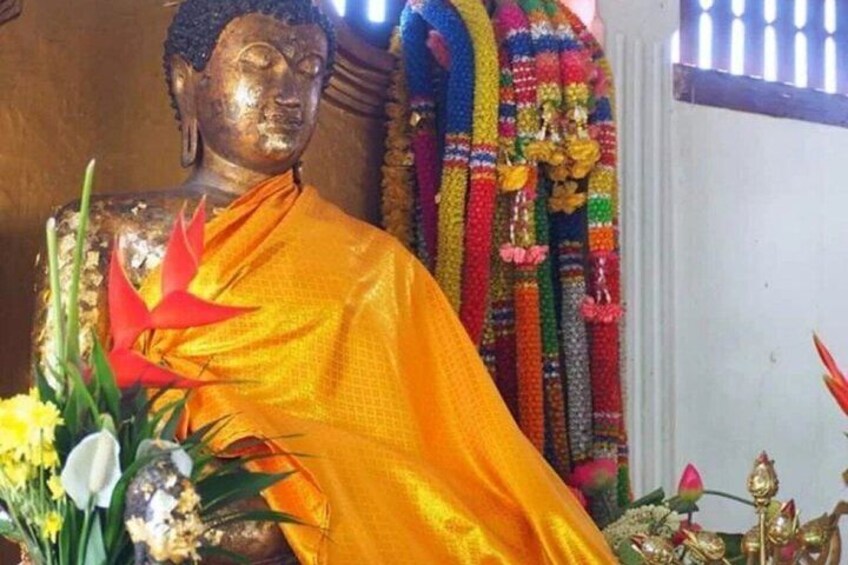 A statue of a seated figure in traditional attire, surrounded by flowers and colorful decorations. 4