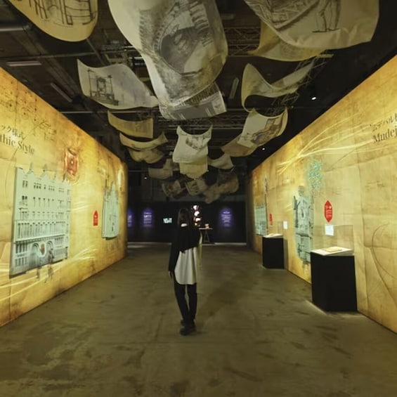 A person standing in a museum with walls covered in architectural drawings and models. 2