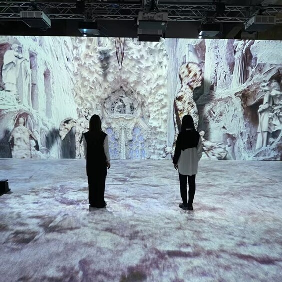 Two people standing in front of a large digital display with a snowy landscape. 5