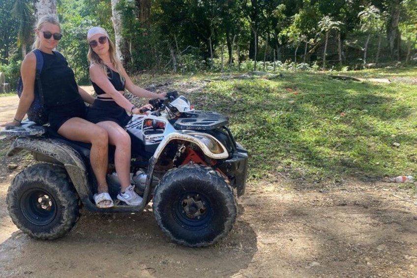 Two people on an ATV in a forested area. 4