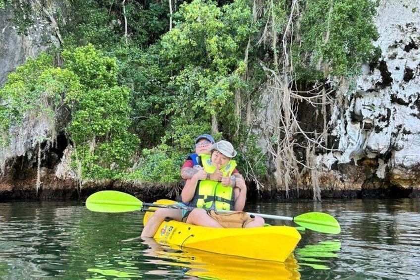 Two people kayaking in a yellow boat on a river surrounded by lush greenery and rocky cliffs. 5
