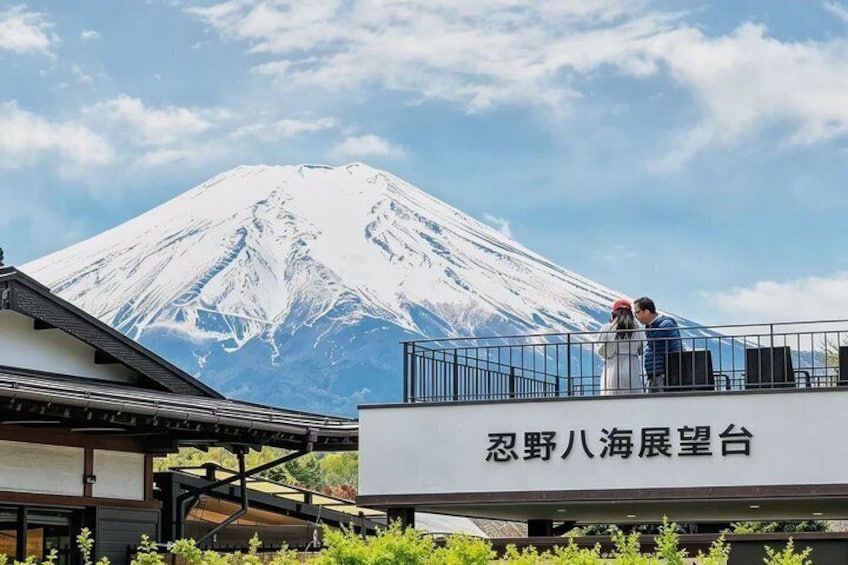 A snow-capped mountain, a couple on a balcony, and a sign with Japanese characters. 1