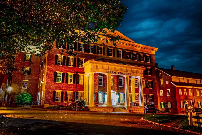 A historic building with a prominent entrance labeled 'Salem College' at night. 1