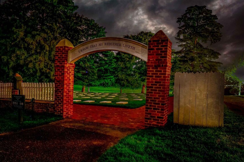 A cemetery gate with a brick archway and a plaque. 3