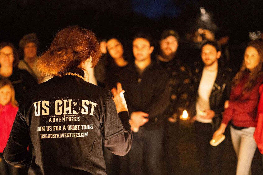 A group of people gathered around a person wearing a jacket with text on the back. 5