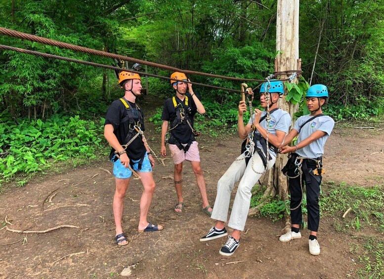 Four people in helmets and harnesses on a rope bridge in a forest. 2