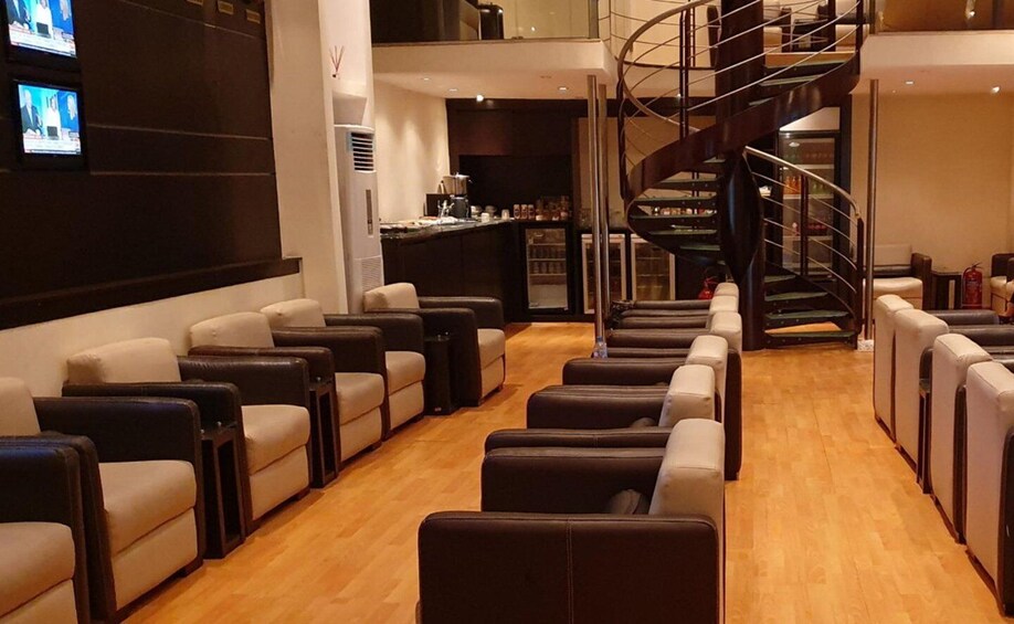 A modern interior with leather chairs, a spiral staircase, and a bar area. 1