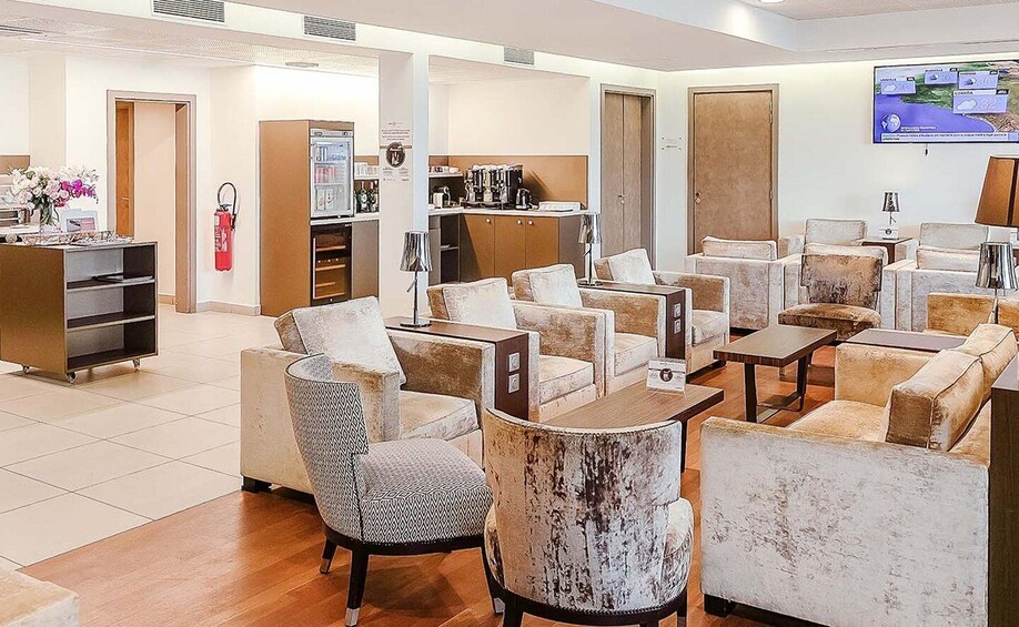 A modern lounge area with sofas, armchairs, and a coffee station. 2