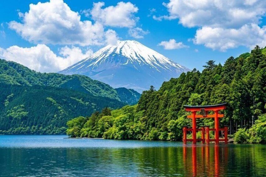 A serene lake with a red torii gate, lush greenery, and a snow-capped mountain in the background. 1