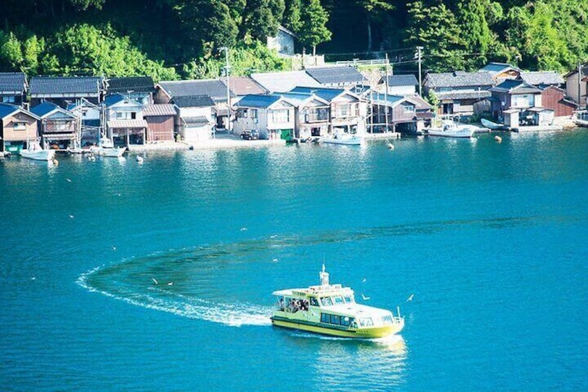 A boat moving through a calm body of water with houses and boats docked along the shore. 2