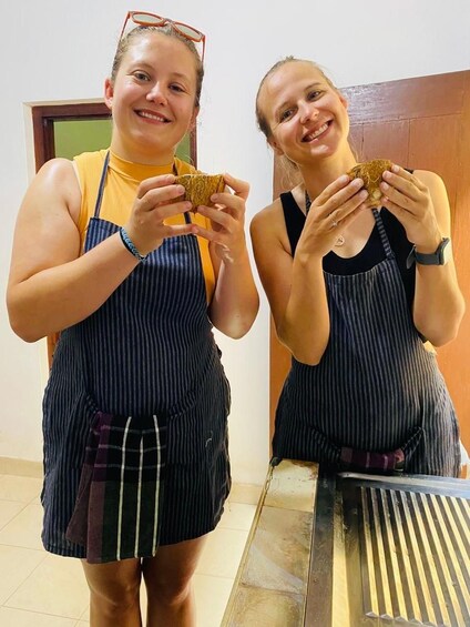 Two individuals wearing striped aprons, holding what appears to be food items. 5