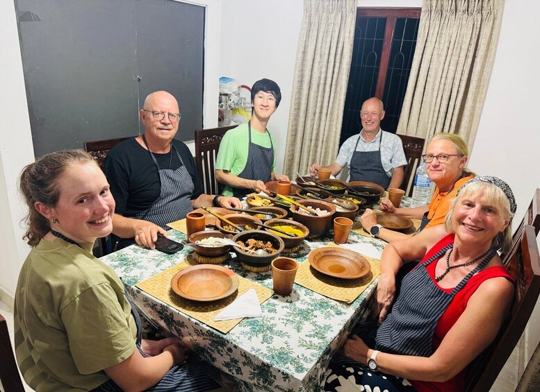 A group of people around a table with various dishes and utensils, suggesting a meal or cooking activity. 1