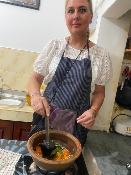 A person in a kitchen, stirring a pot on a stove. 4