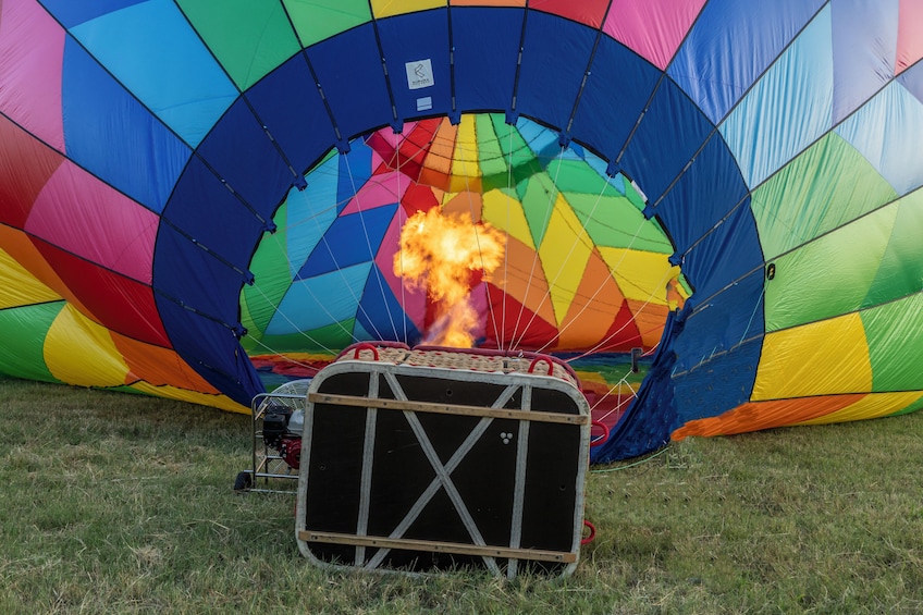 A colorful hot air balloon with a basket and a fire burning inside it. 3