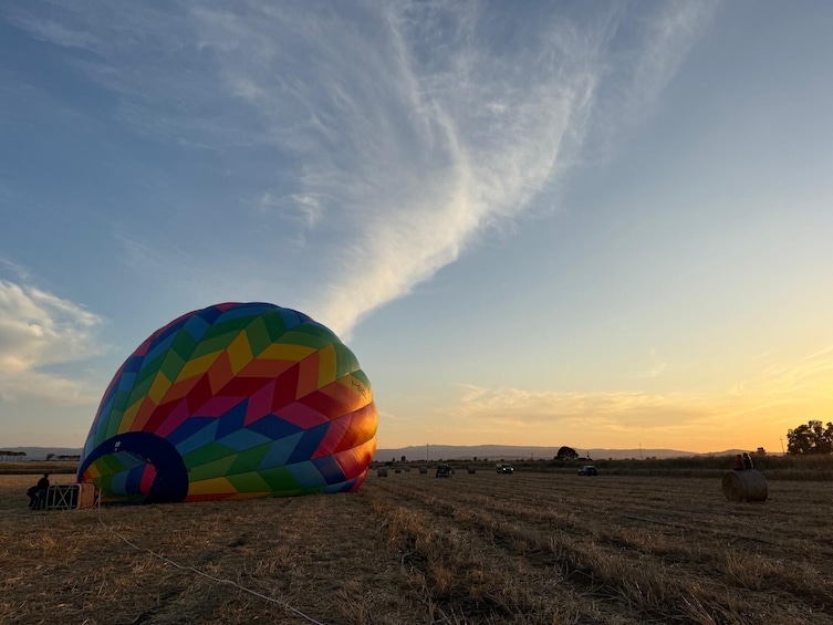 A colorful hot air balloon in a field with a sunset in the background. 5