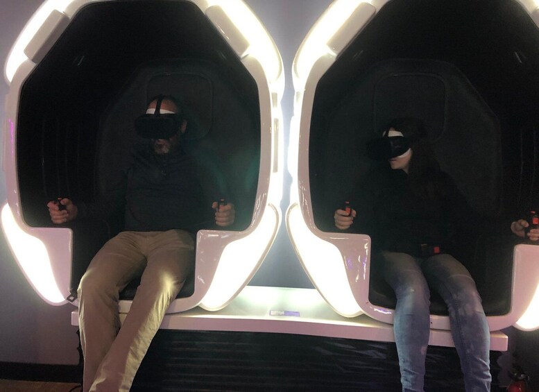 Two individuals seated in illuminated booths, each holding a red object. 3