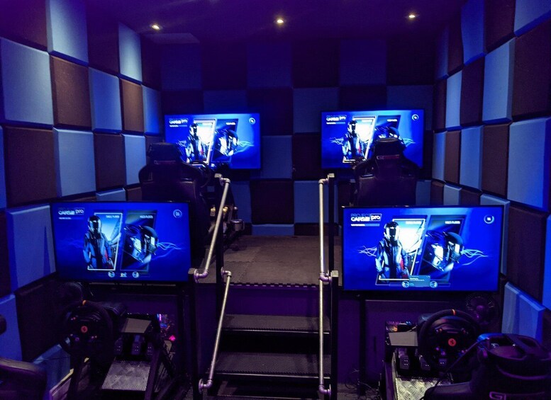 A soundproofed room with multiple monitors displaying the same image, a gaming chair, and a gaming console. 1