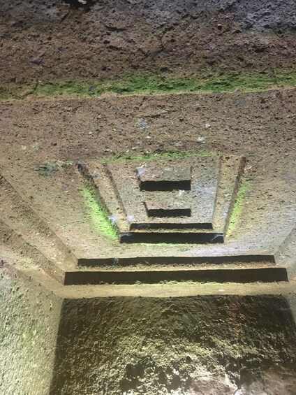 A staircase leading downwards with a rough, uneven surface and patches of green moss. 2