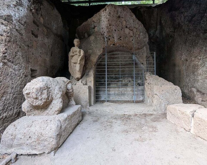 A stone statue, a lion head, and a metal gate in a cave. 5