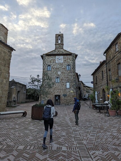 A stone tower with a clock, surrounded by cobblestone streets and traditional buildings. 1