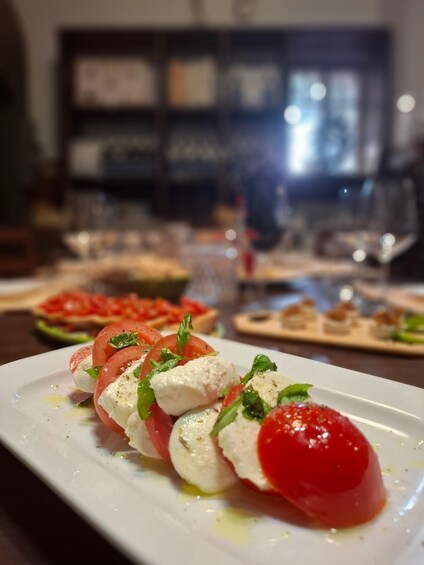 A plate of Caprese salad with tomatoes, mozzarella, and basil, with a blurred background of a dining setting. 5