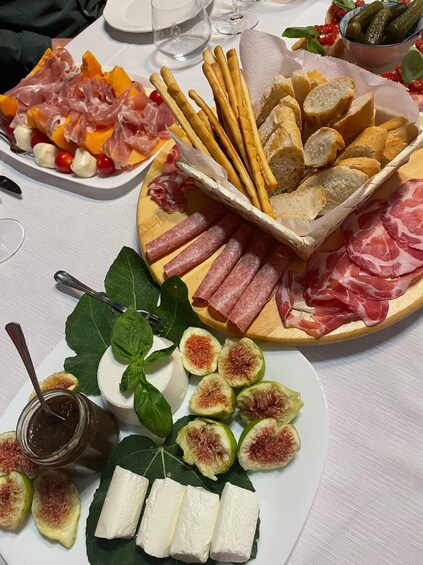 A variety of food items including cured meats, breadsticks, figs, and cheese on a table. 2